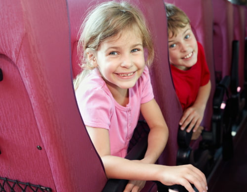 Two children smile while sitting in a charter bus